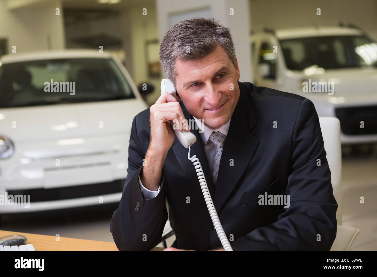 Imprenditore sorridente con notebook sul telefono Foto Stock