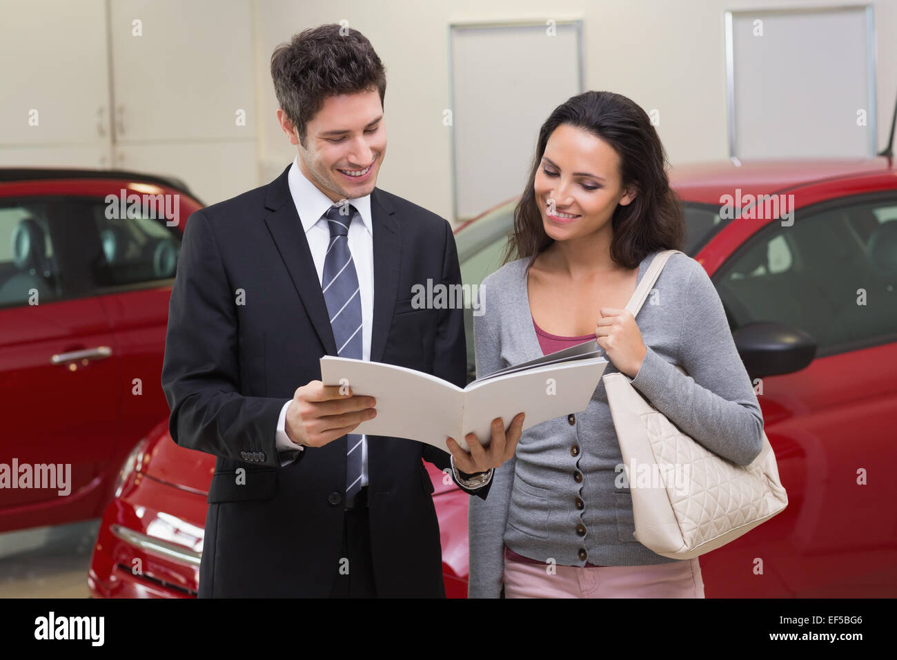 Venditore mostra brochure per il cliente e sorridente Foto Stock