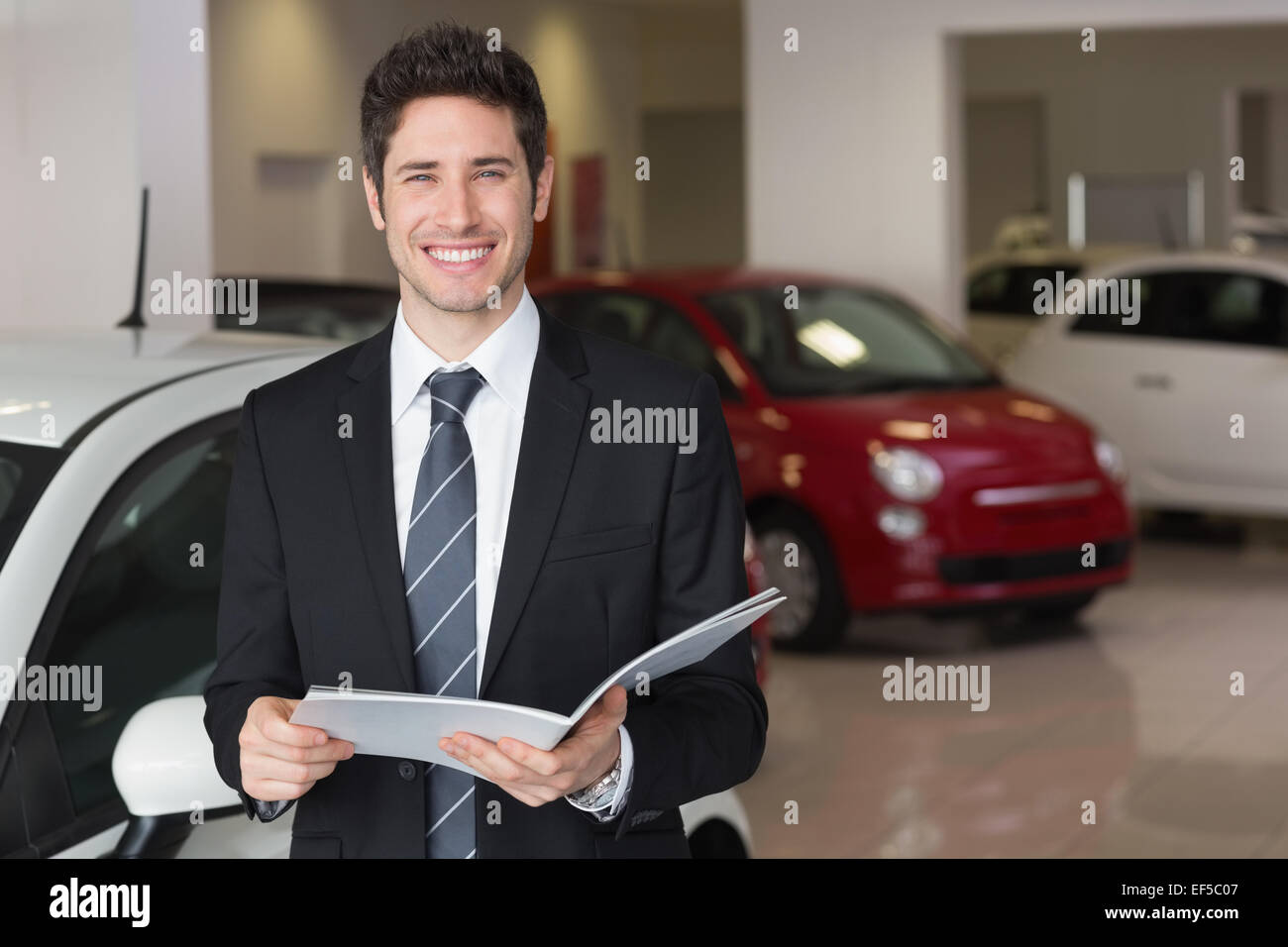 Imprenditore la lettura su un opuscolo sorridente in telecamera Foto Stock