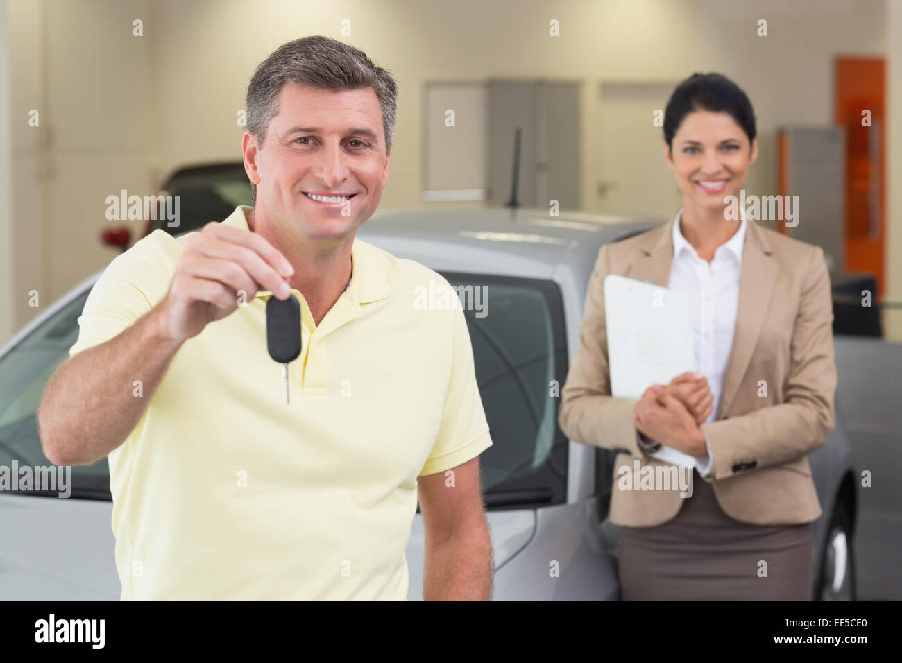 Cliente sorridente che mostra la sua nuova chiave auto Foto Stock