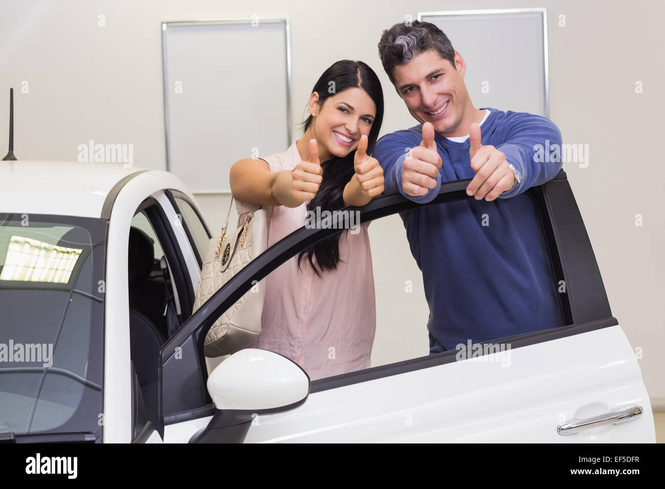 Coppia sorridente in piedi mentre dando pollice in alto Foto Stock