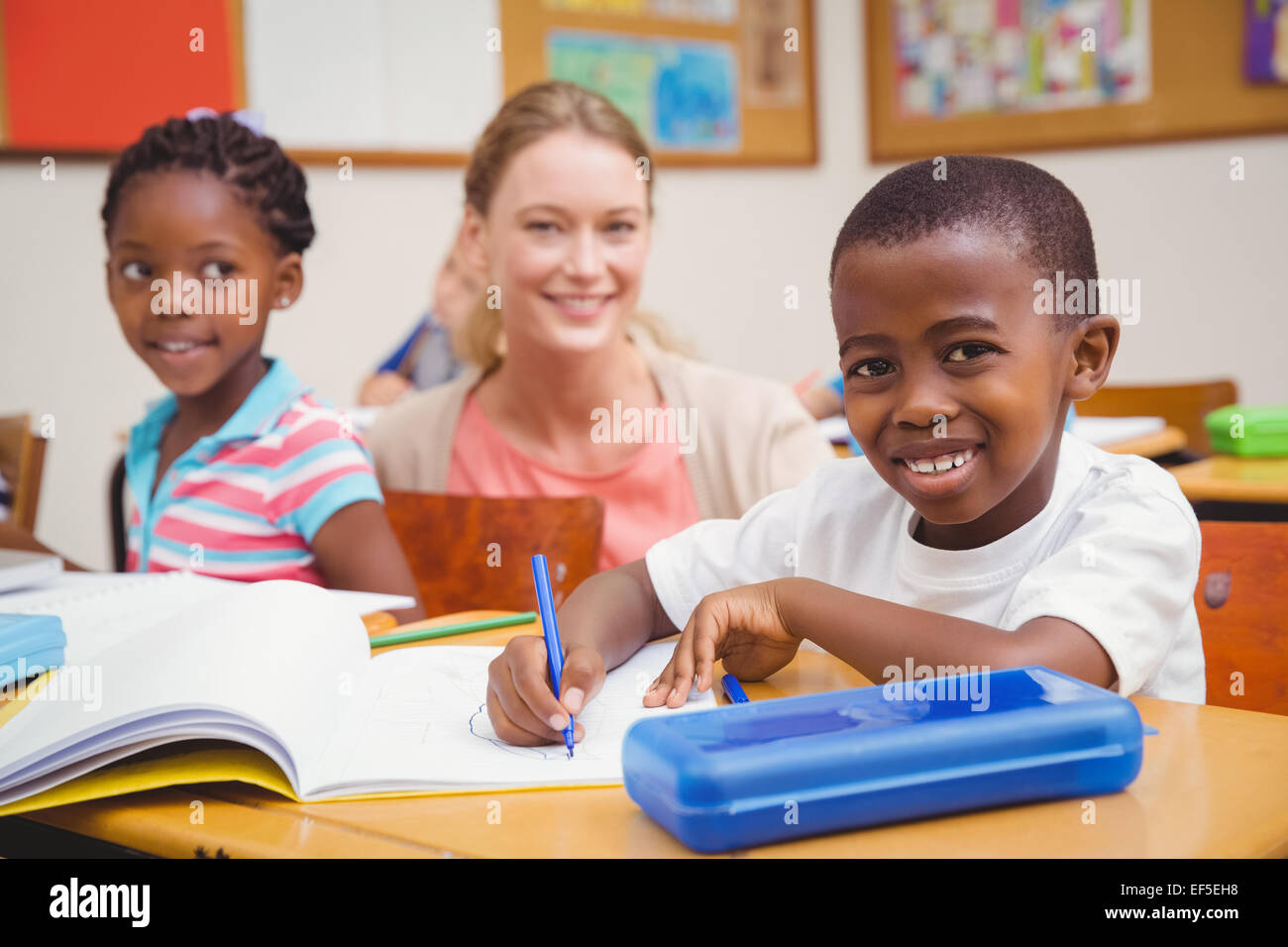 Piuttosto insegnante aiutando la pupilla in aula Foto Stock