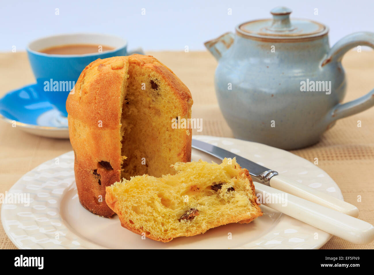 Una fetta di panettone tradizionale italiana frutto di Natale torta di pane su una piastra con una tazza di tè e teiera su un tavolo. Inghilterra, Regno Unito Foto Stock