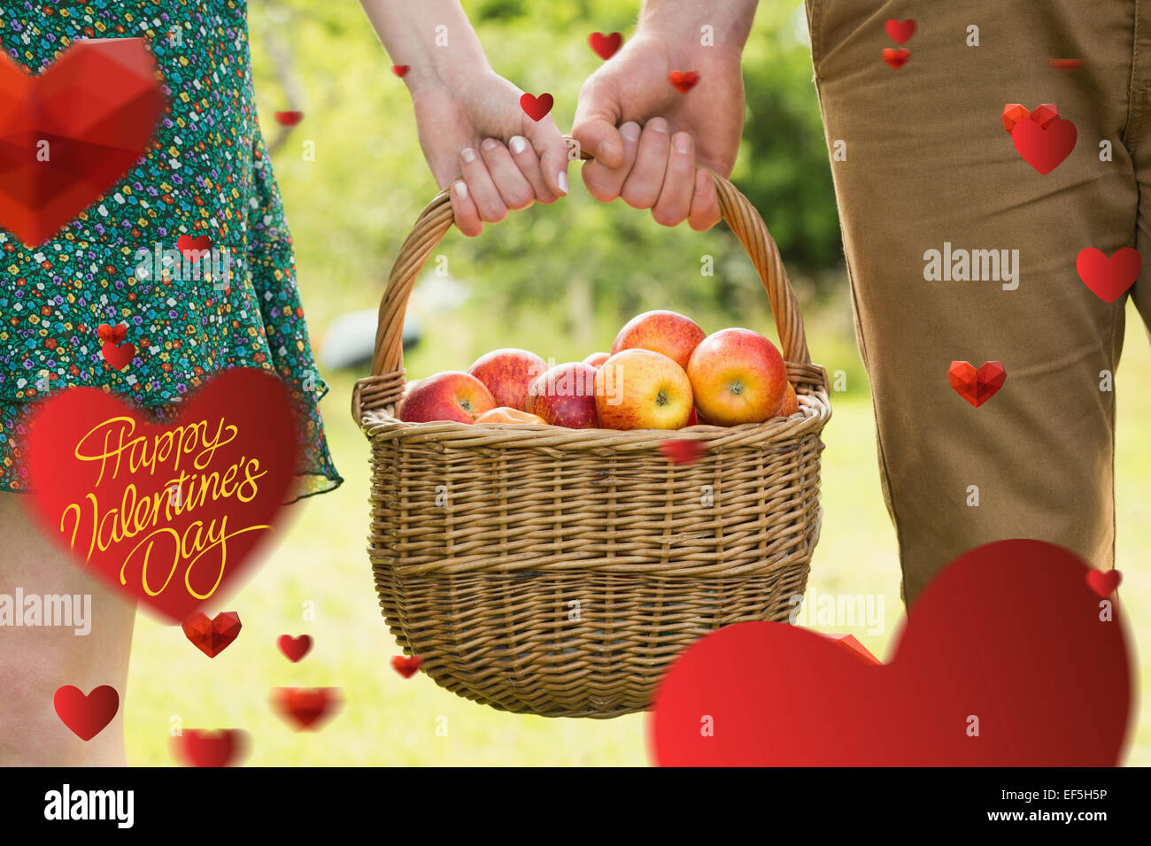 Immagine composita del cesto di mele essendo portato da una giovane coppia Foto Stock