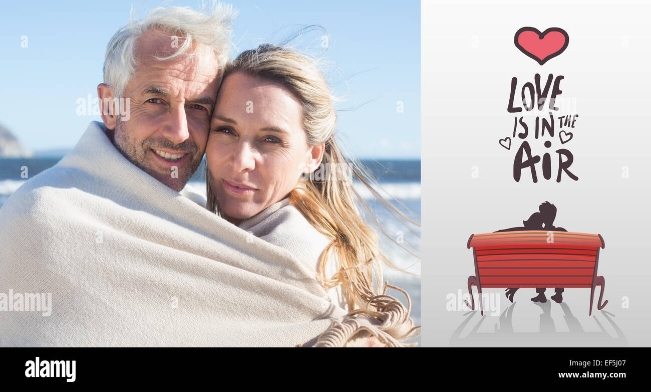 Immagine composita di sorridere giovane avvolto in un lenzuolo sul beach Foto Stock