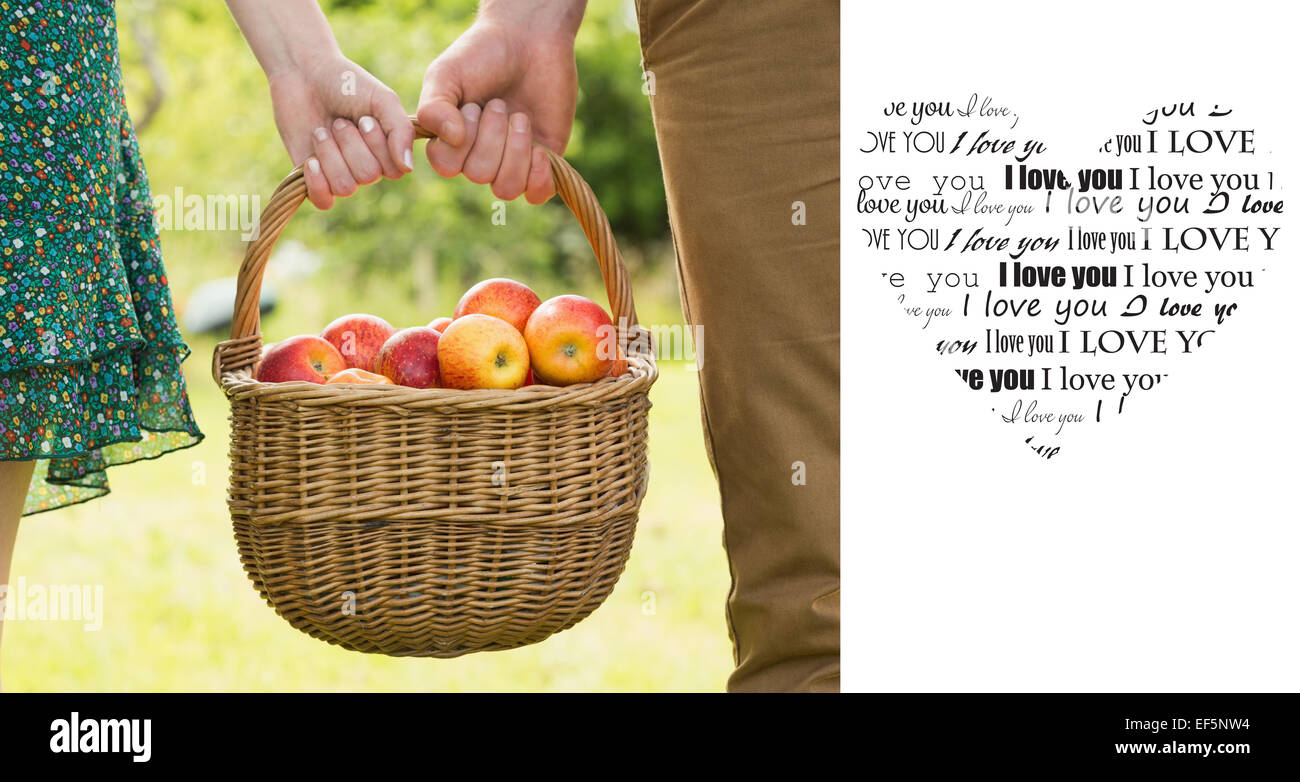 Immagine composita del cesto di mele essendo portato da una giovane coppia Foto Stock