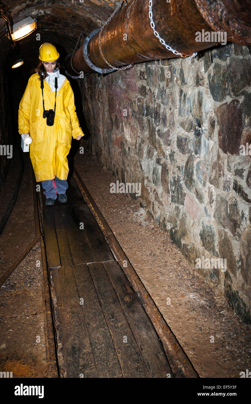 Donna Adulto passeggiate lungo legno strette vie che indossa un casco giallo e rivestire internamente alla fossa miniera in uso dal 1156 fino al 1993 Foto Stock