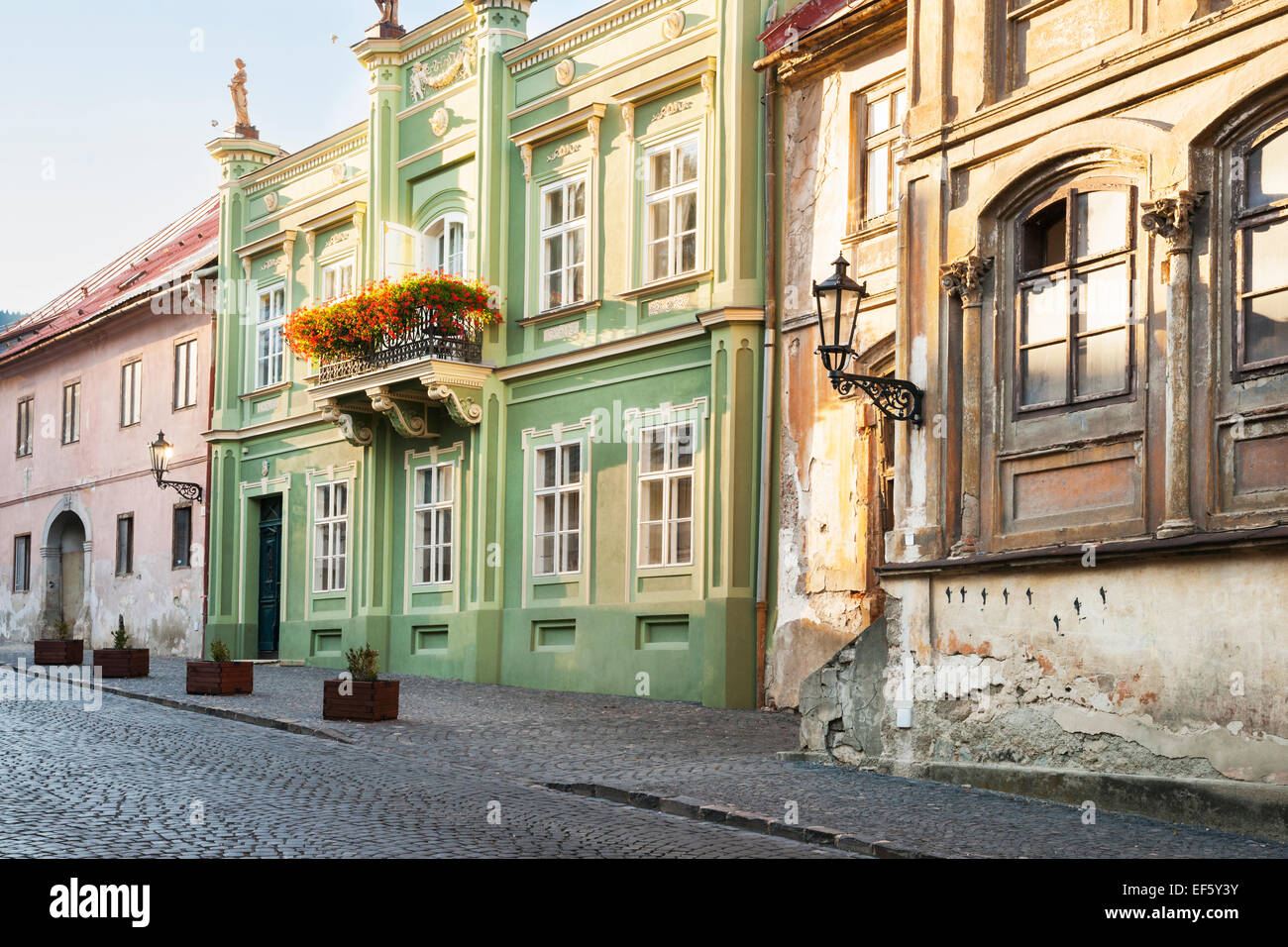 Edifici color pastello con fioriere e lampioni in ferro su una strada di ciottoli in Banska Stiavnica, Slovacchia Foto Stock