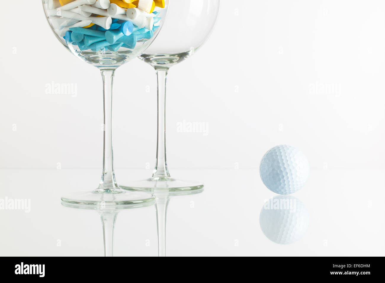Due bicchieri di vino e attrezzature da golf sulla scrivania in vetro Foto Stock