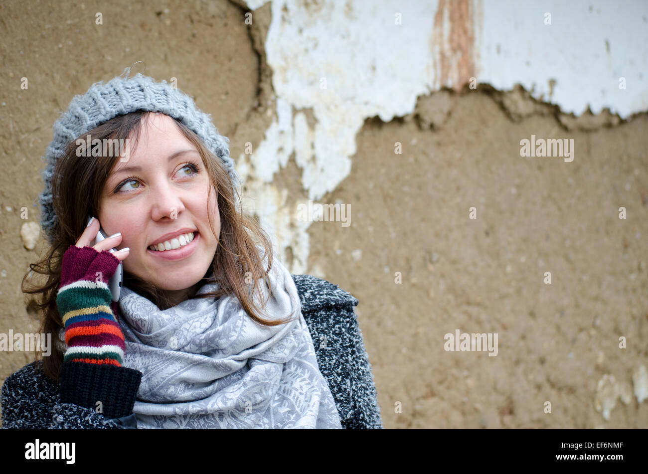 Ragazza giovane parlando al telefono davanti a una rovina il vecchio muro di argilla Foto Stock