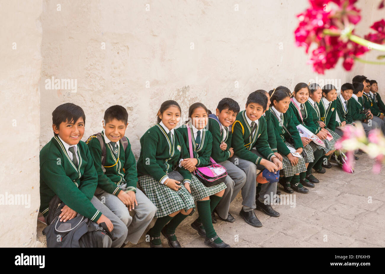 Locali peruviani felice scolari in uniforme scolastica seduta su una panchina divertirsi godendosi la visita di Santa Catalina convento in Arequipa, Perù Foto Stock