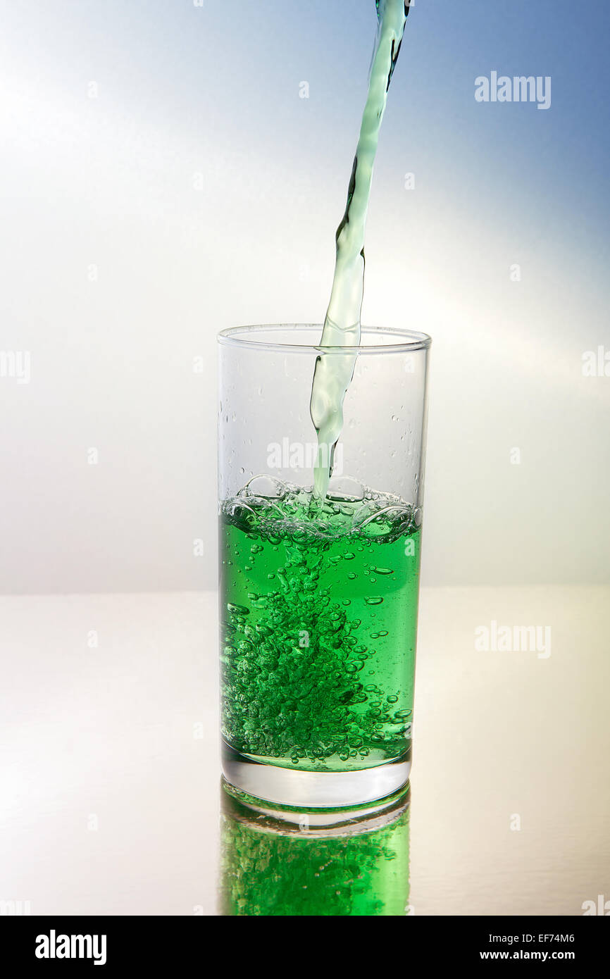 Il verde il liquido viene versato in un bicchiere Foto Stock