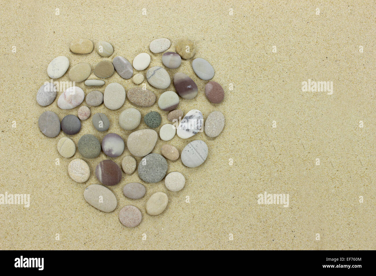 Cuore fatta di pietre di spiaggia su una spiaggia di sabbia Foto Stock