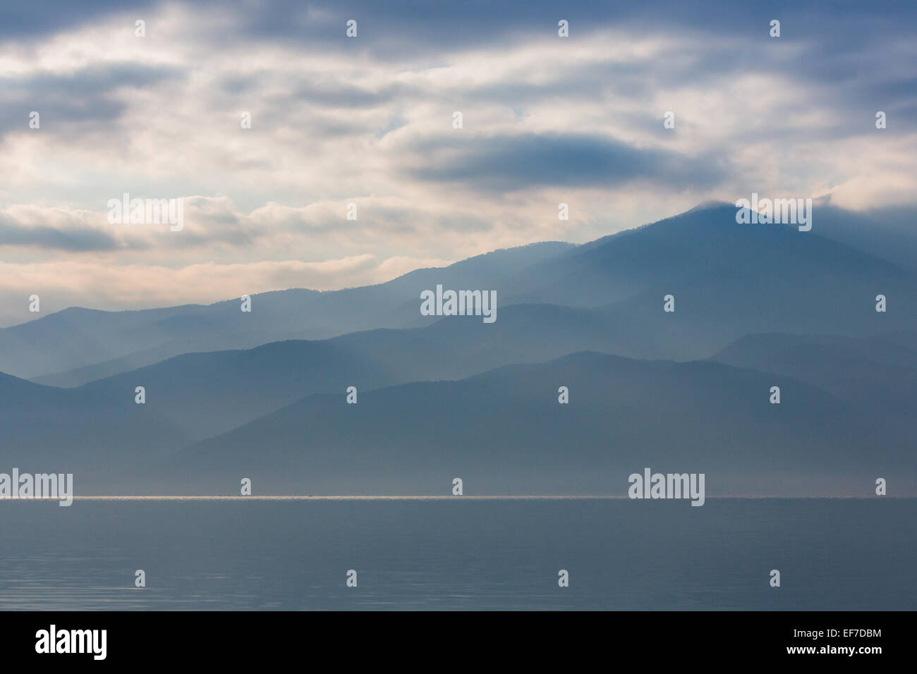 Misty stratificato retroilluminato colline all'alba sul lago di Kerkini nella Grecia settentrionale Foto Stock