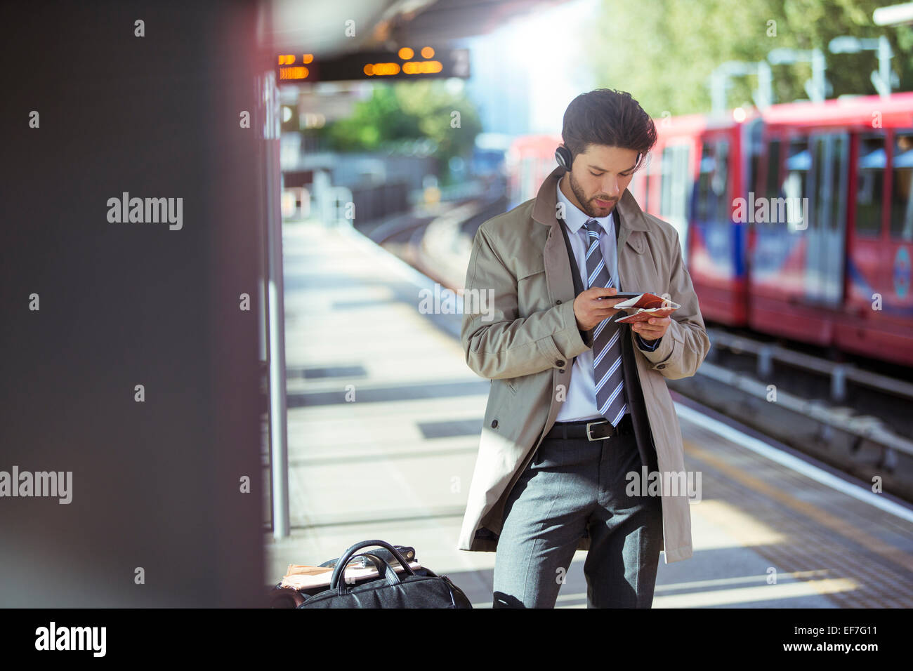 Imprenditore tramite telefono cellulare in una stazione ferroviaria Foto Stock