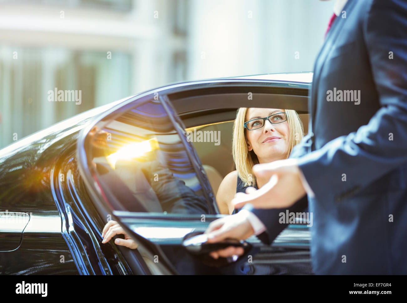 Chauffeur apertura porta auto per imprenditrice Foto Stock