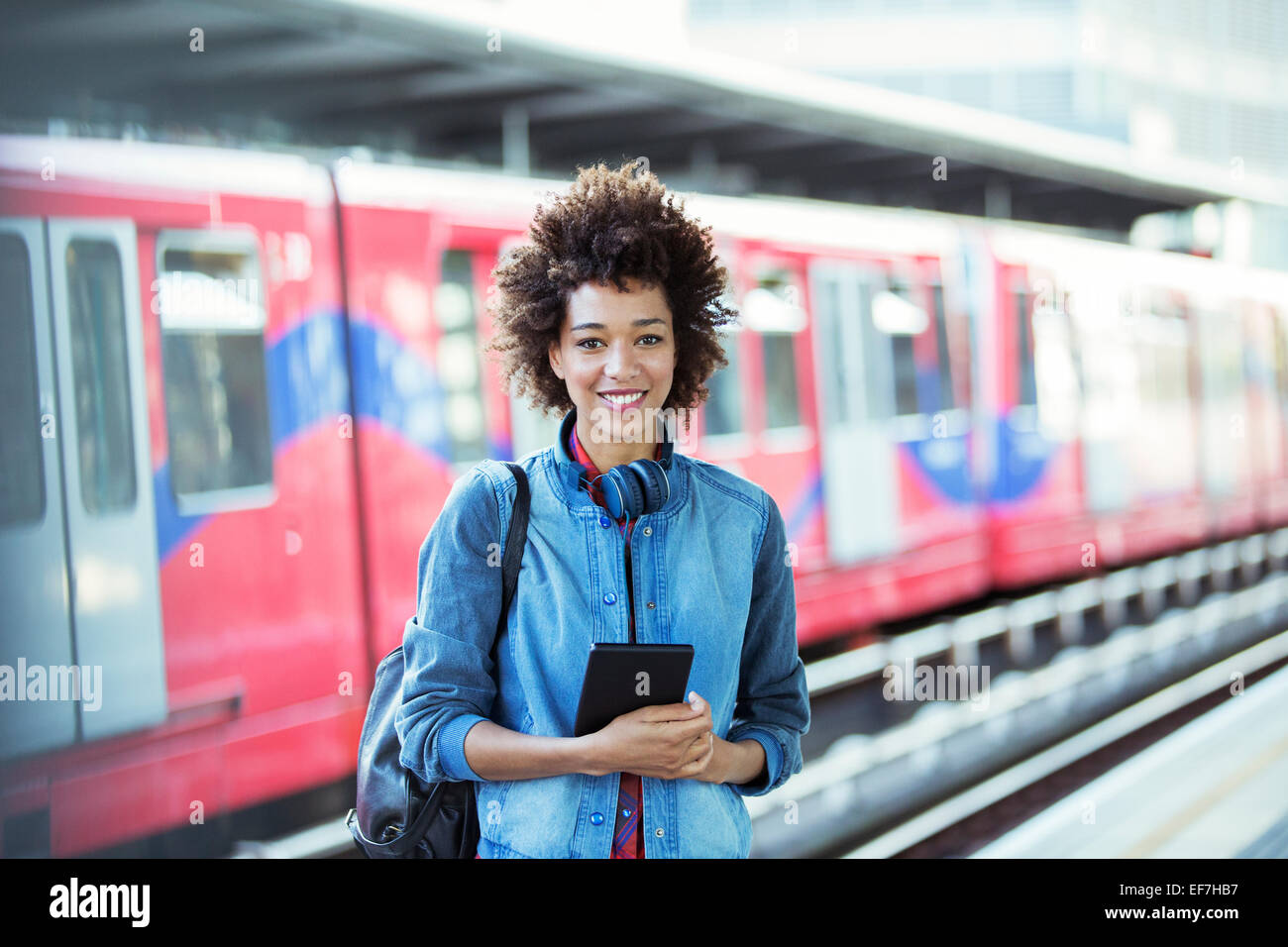 Donna sorridente in piedi nella stazione ferroviaria Foto Stock