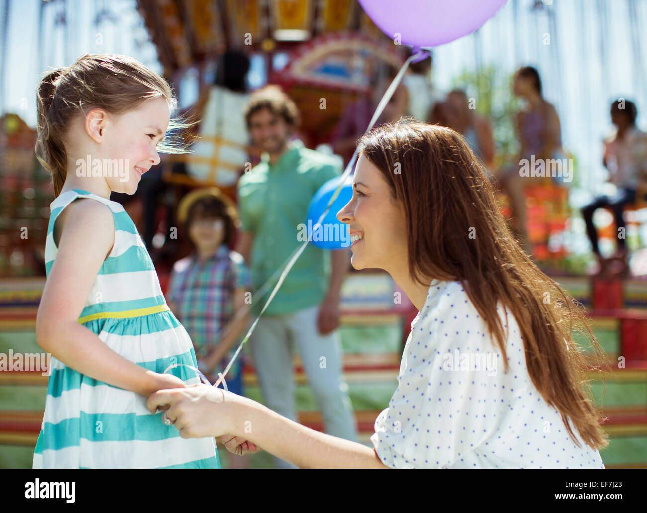 La madre e la ragazza con palloncino guardando ogni altro nel parco di divertimenti Foto Stock