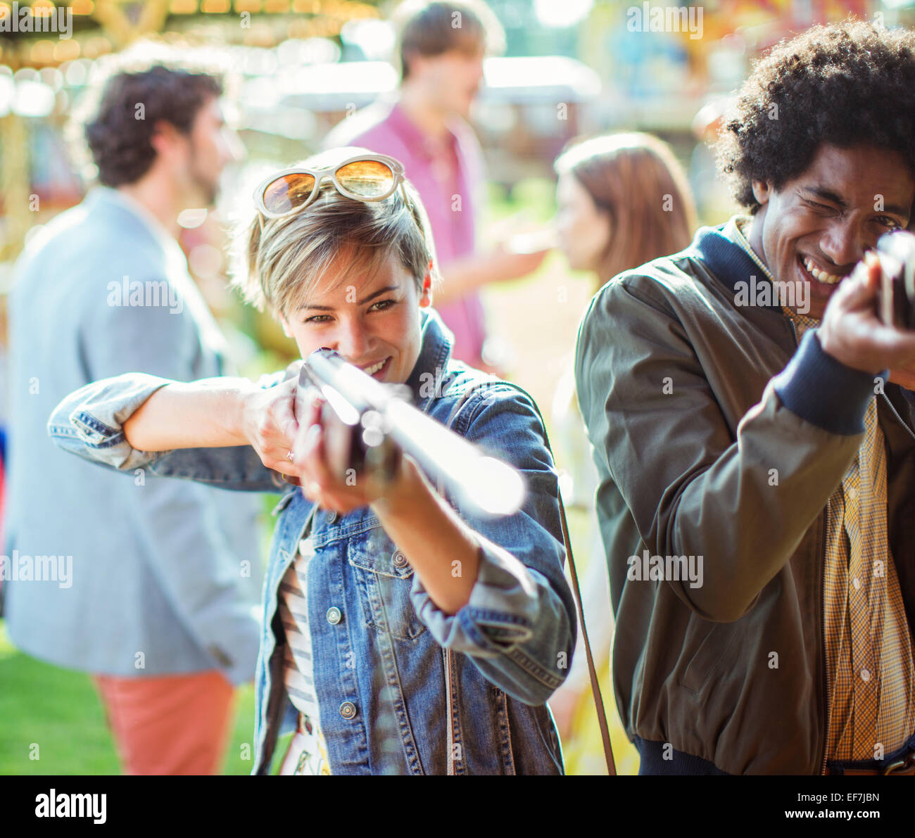 Coppia giovane mirando con armi da fuoco nel parco di divertimenti Foto Stock