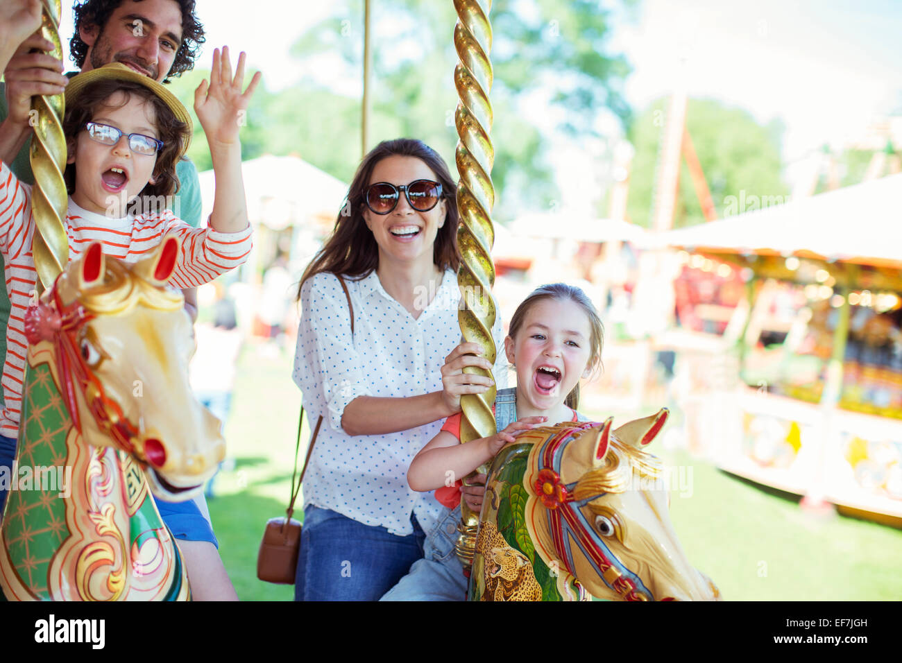 Famiglia sulla giostra nel parco dei divertimenti Foto Stock