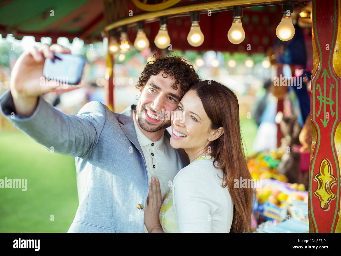 Coppia sorridente tenendo selfie nel parco di divertimenti Foto Stock