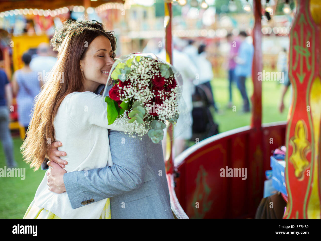 Donna che mantiene bouquet e abbracciare il suo fidanzato nel parco di divertimenti Foto Stock
