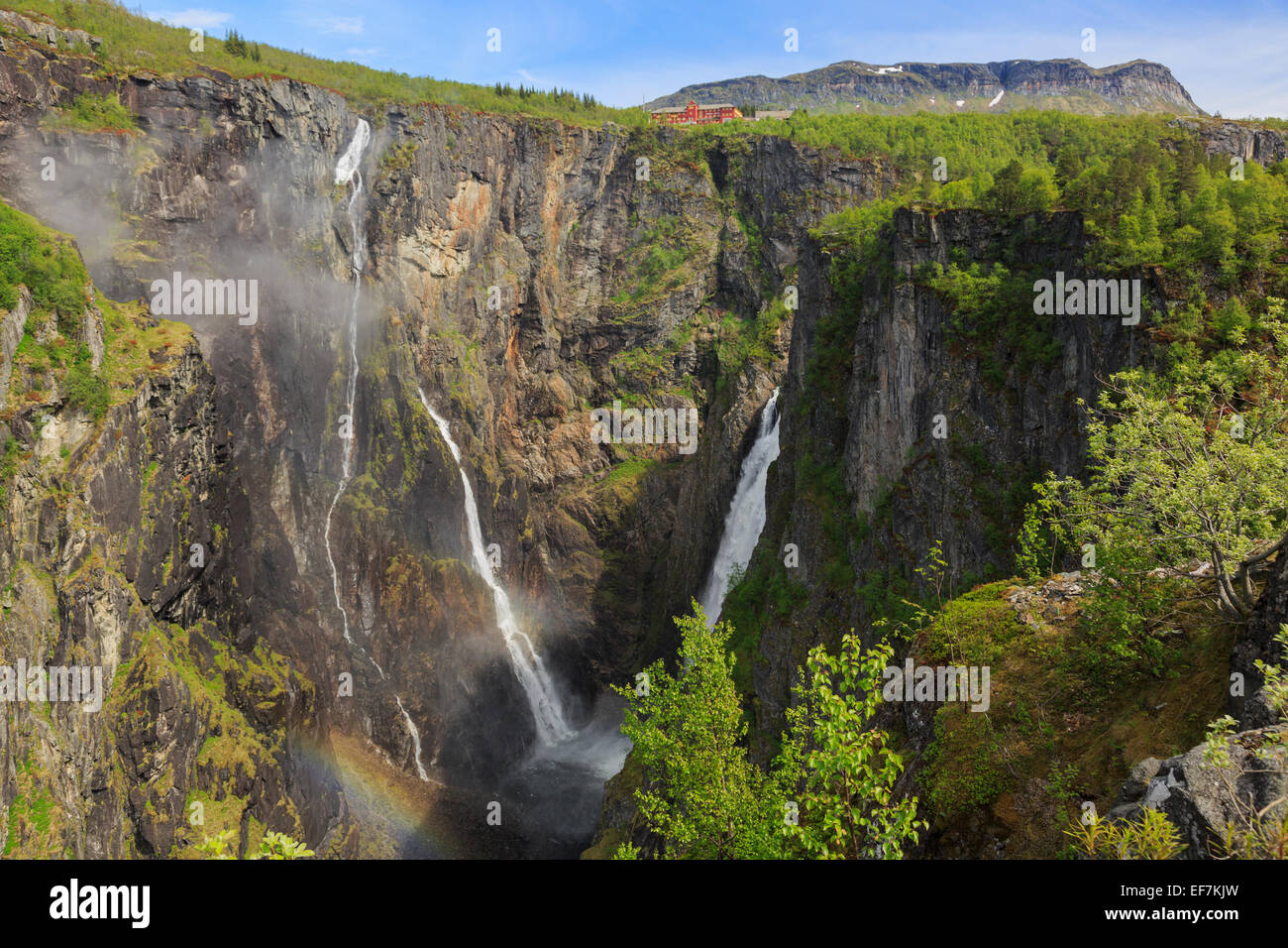 Spray formando un arcobaleno a cascata Vøringfossen con Fossli Hotel su una scogliera. Vøringfoss Måbø valley, Eidfjord, Norvegia Foto Stock