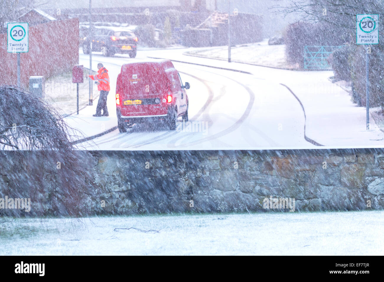 Lochwinnoch, Renfrewshire, Scozia, Regno Unito. 28 gennaio 2015. Regno Unito Meteo: Con la neve pesante prevista per cadere durante la notte inizia a coprire il terreno come un postino raccoglie le lettere da una casella di posta Foto Stock
