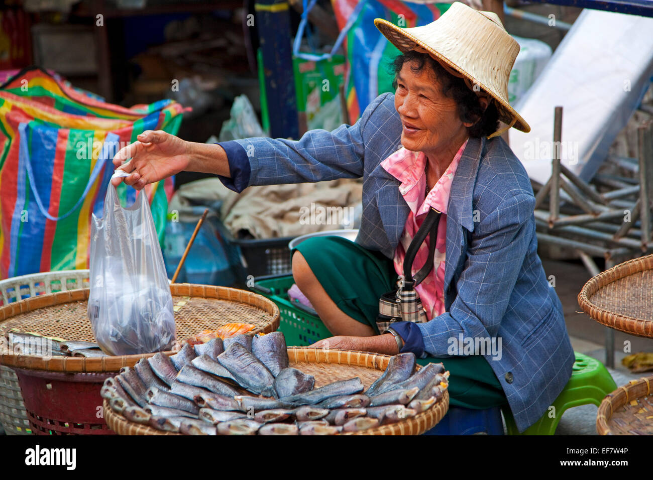 Anziana donna tailandese tradizionale con vimini palm hat la vendita del pesce al mercato alimentare in Ayutthaya, Thailandia Foto Stock