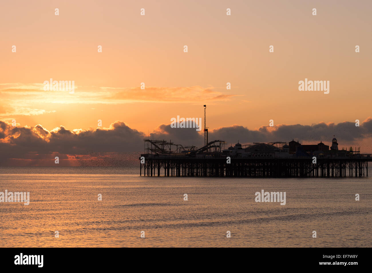 Sole che tramonta dietro la silhouette del Palace Pier Foto Stock