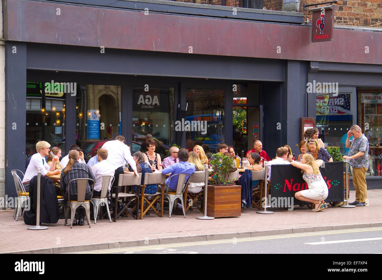 Persone mangiare e bere a al di fuori di Nando's. Carlisle, Cumbria, Inghilterra, Regno Unito. Foto Stock