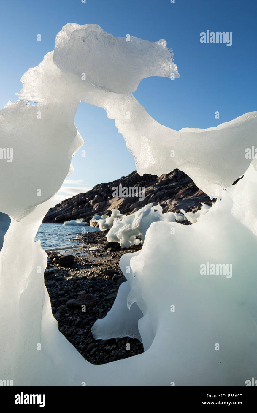 Canada, Nunavut Territorio, impostando il sole di mezzanotte luci iceberg di fusione cordato a bassa marea nel canale di congelati a bordo settentrionale o Foto Stock