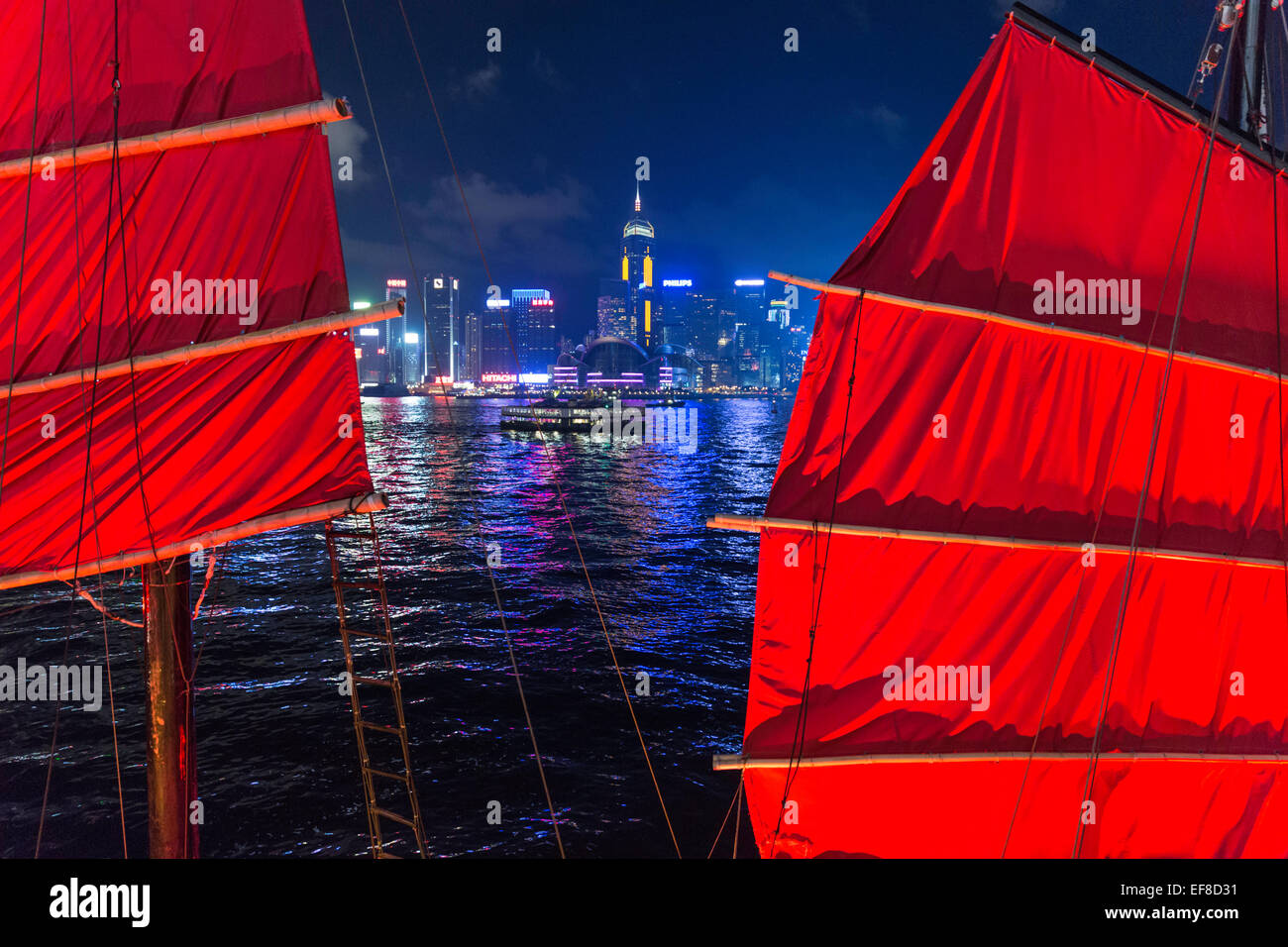 Vista notturna della skyline di Hong Kong dal lato di Kowloon con vele di indesiderata in primo piano Foto Stock