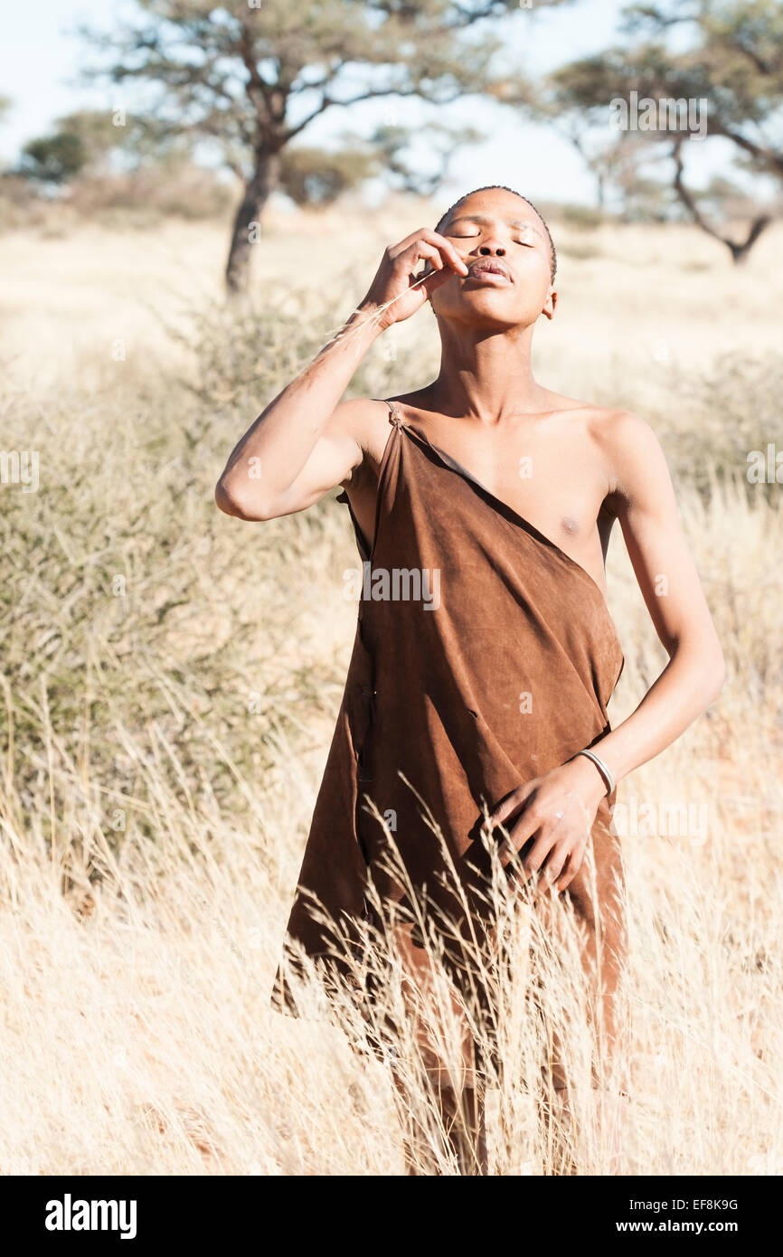 Un giovane Boscimane utilizza un pezzo di seta di erba come stuzzicadenti, Kalahari Namibia del sud Africa Foto Stock