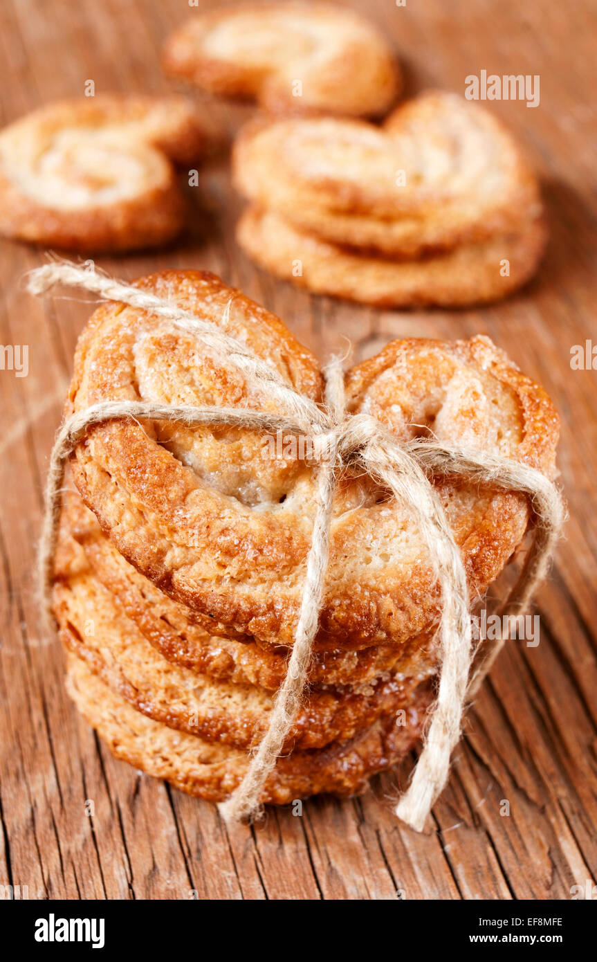 Alcuni palmeras, spagnolo palmier pasticcini, legato con una stringa su una tavola in legno rustico Foto Stock