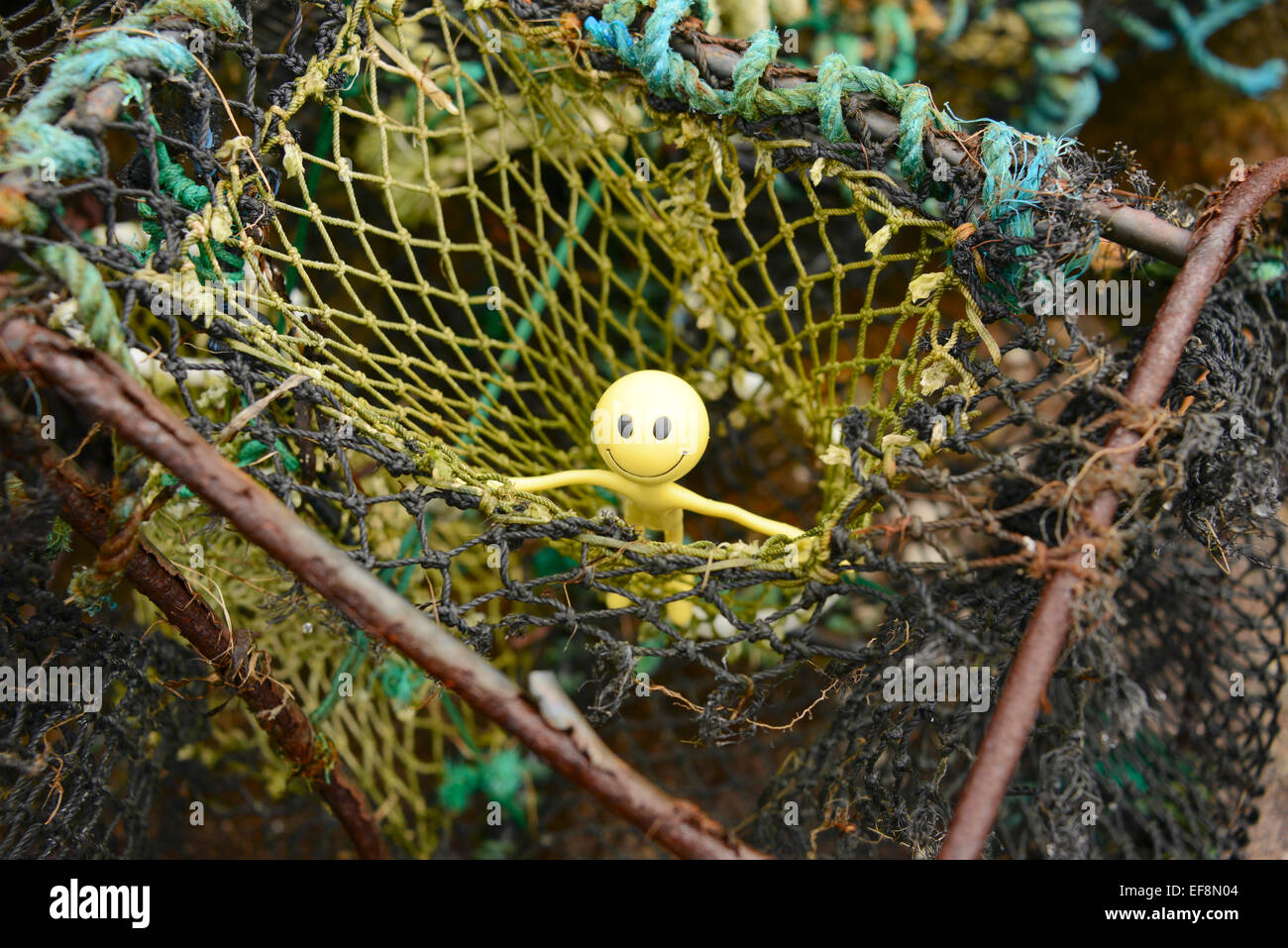 Gialli Smiley uomo in vacanza nelle Ebridi Esterne - qui egli sta cercando di salire al di fuori di un lobster pot Foto Stock