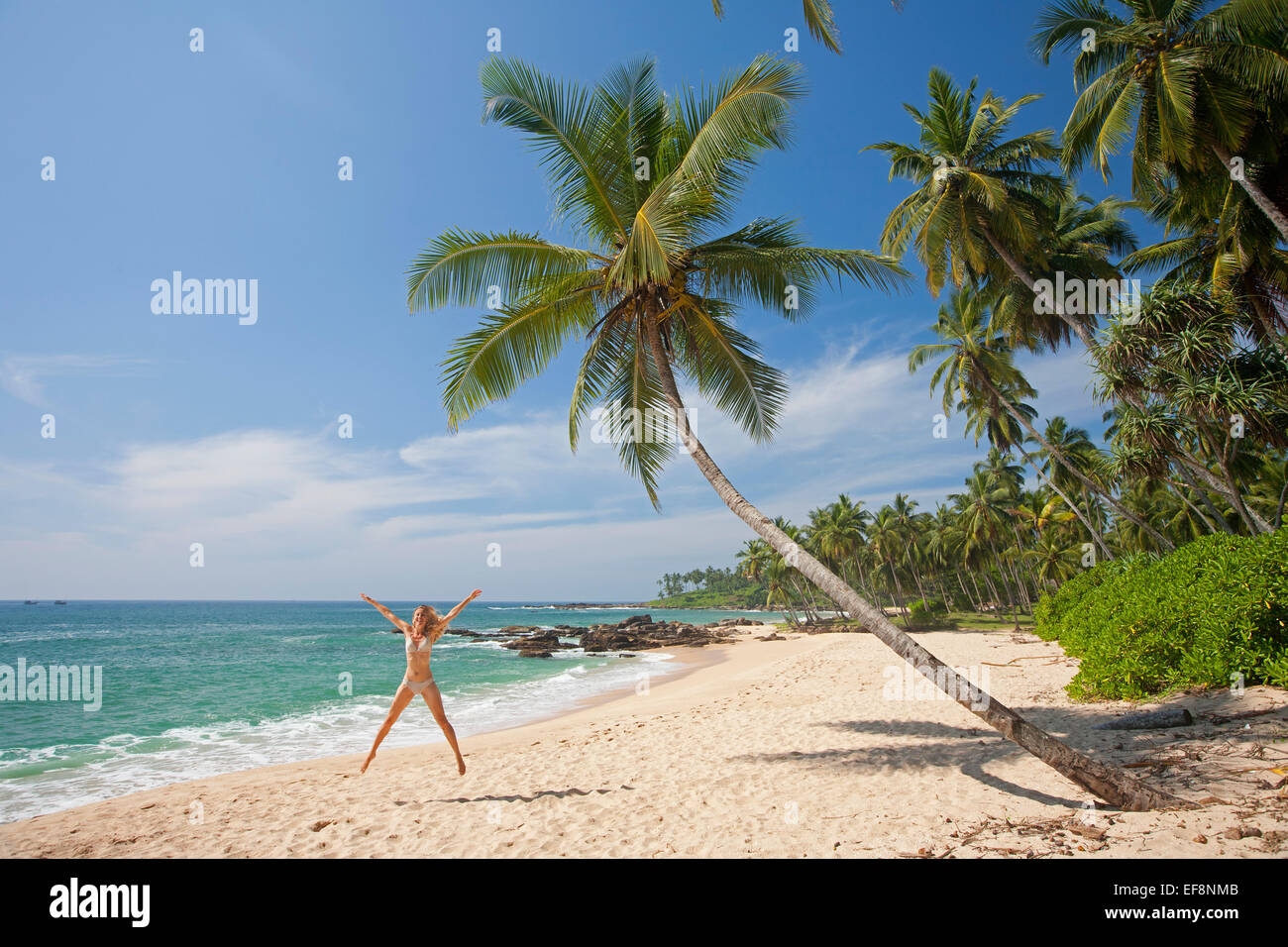 Donna stella facendo saltare sulla spiaggia deserta di TANGALLA Foto Stock