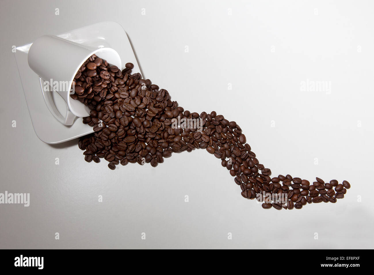 Bianco giacente tazza di caffè con caffè in grani Foto Stock