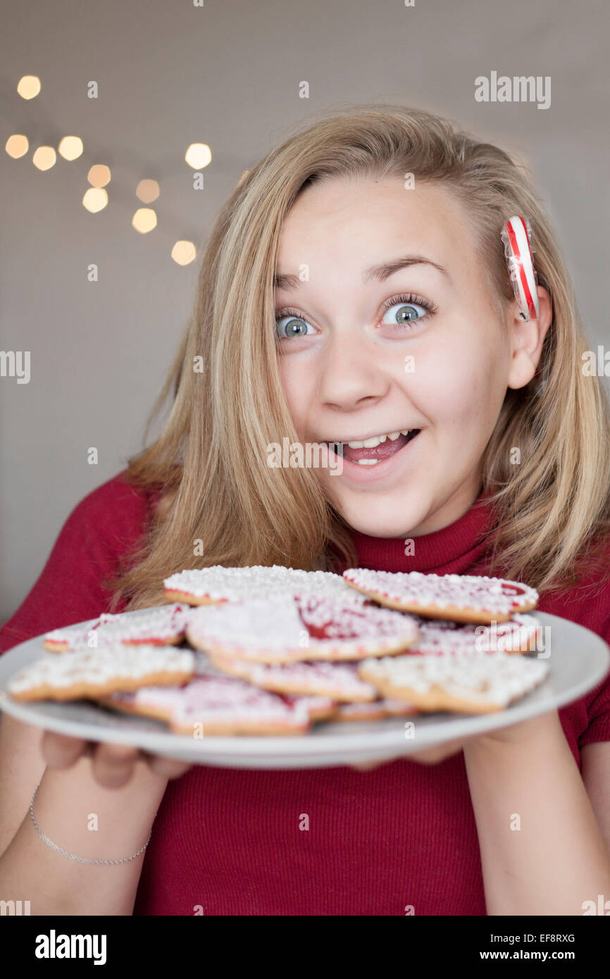 Ragazza sorridente (14-15) tenendo la piastra dei biscotti di Natale Foto Stock