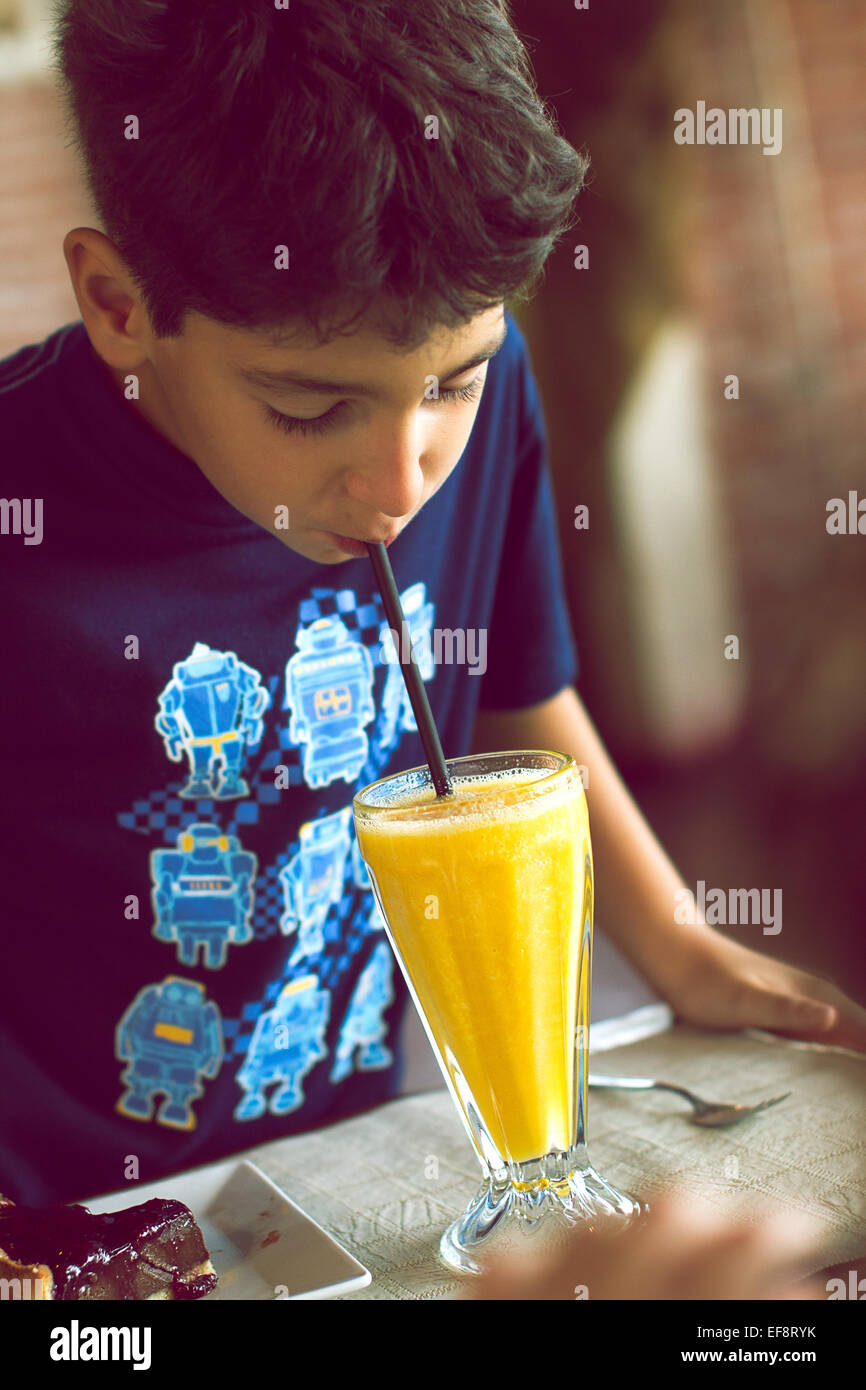 Ritratto del ragazzo che beve succo d'arancia con la cannuccia Foto Stock
