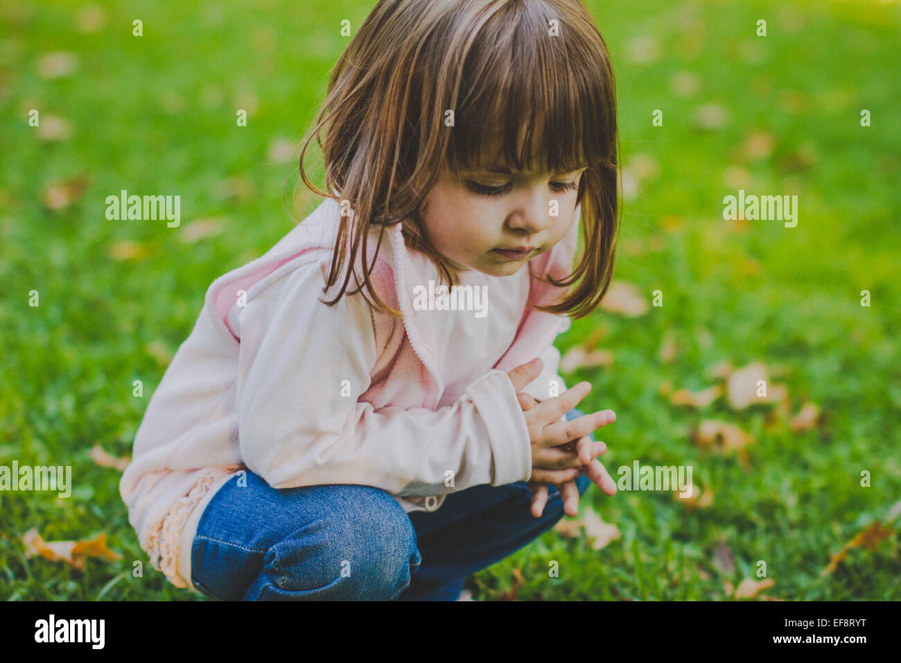 Ritratto di ragazza accovacciata in un parco pubblico Foto Stock