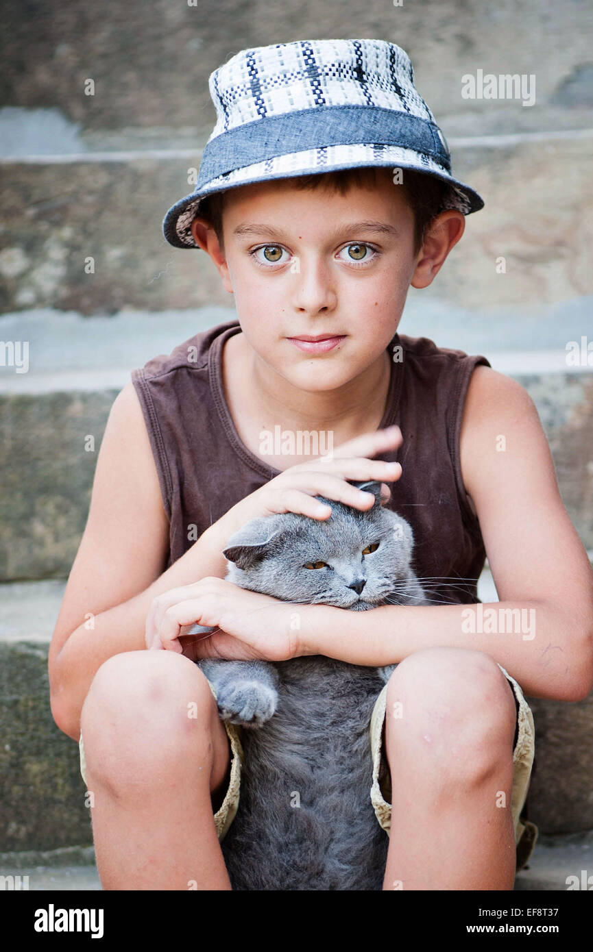 Ritratto di ragazzo (8-9) seduto sui gradini con cat Foto Stock