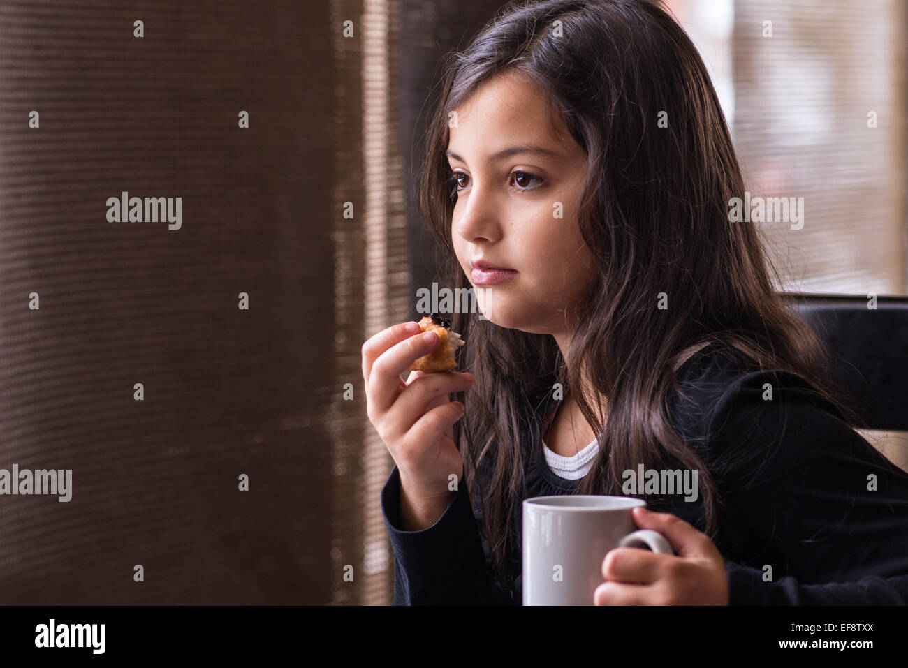 Ragazza seduta nella caffetteria con una tazza di cioccolata calda e una fetta di torta Foto Stock