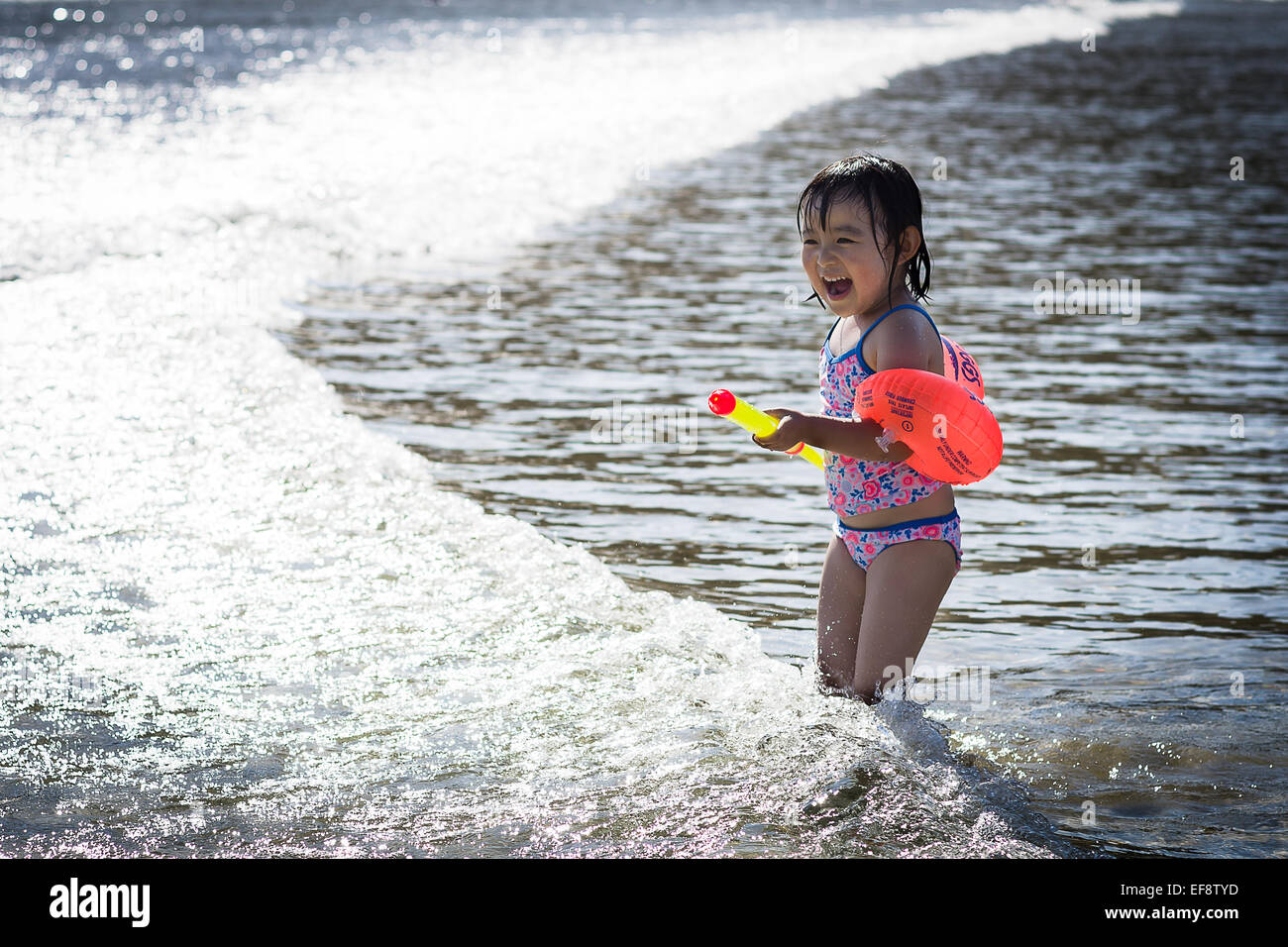 Ragazza indossando costume da bagno e acqua rosso ali giocando in mare increspato Foto Stock