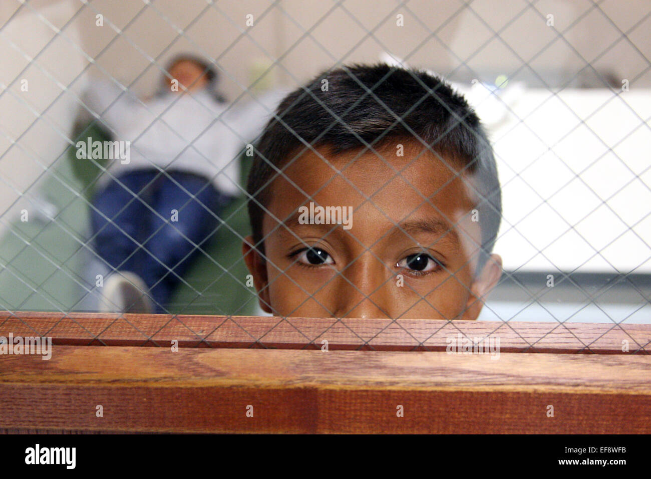 Un giovane ragazzo messicano guarda fuori da un centro di detenzione in camera dopo essere intercettati illegalmente che attraversano la frontiera degli Stati Uniti il 5 giugno 2014 in Brownsville, Texas. Foto Stock