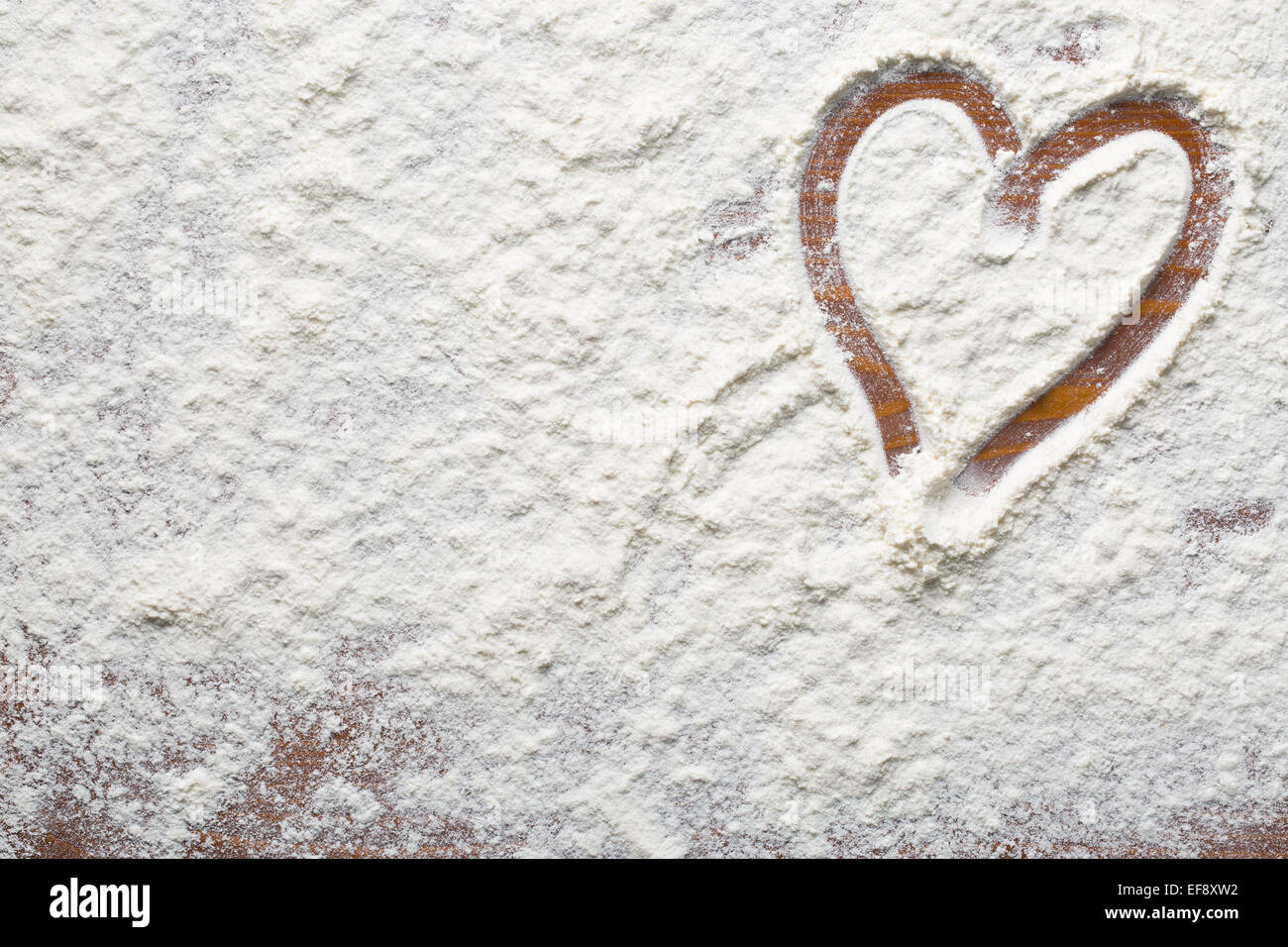 Cuore di farina a fontana sul tavolo di legno Foto Stock