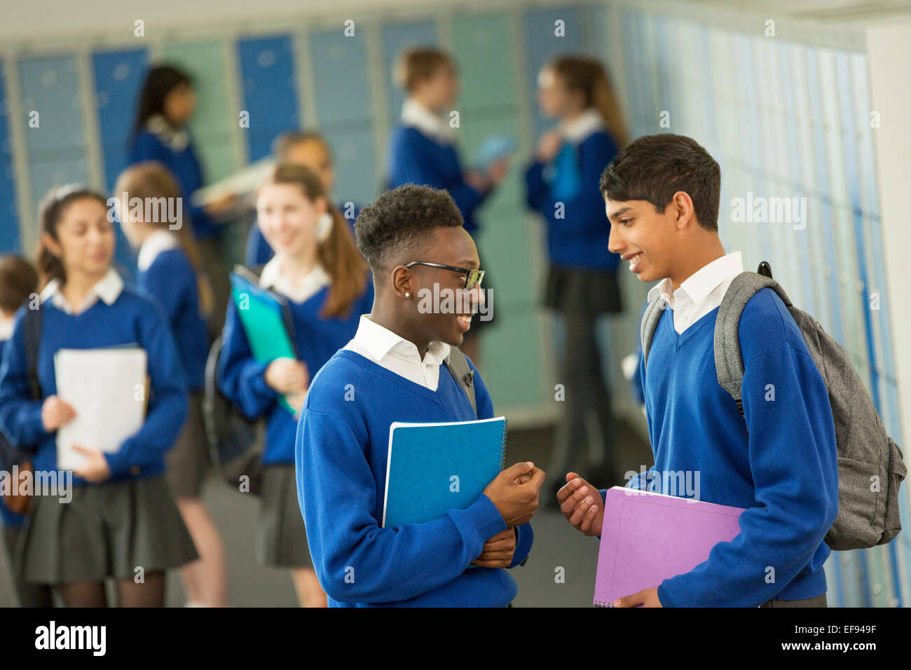 Due gli studenti maschi che indossano uniformi scolastiche parlando in spogliatoio Foto Stock