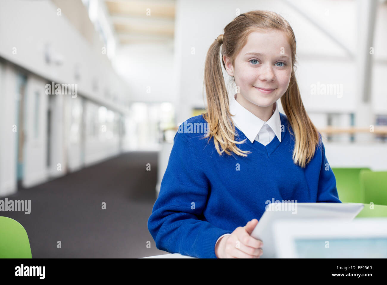 Ritratto di sorridente scuola elementare ragazza bionda con pig-tail holding tavoletta digitale Foto Stock