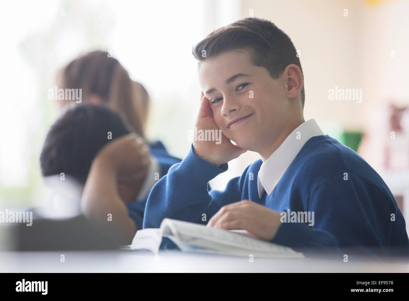 Ritratto di sorridente scuola elementare ragazzo seduto alla scrivania in aula Foto Stock