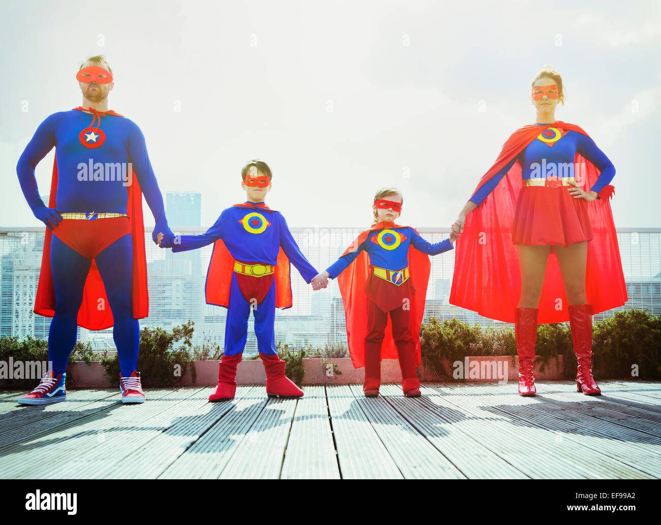 Famiglia di supereroi tenendo le mani sul tetto della città Foto Stock